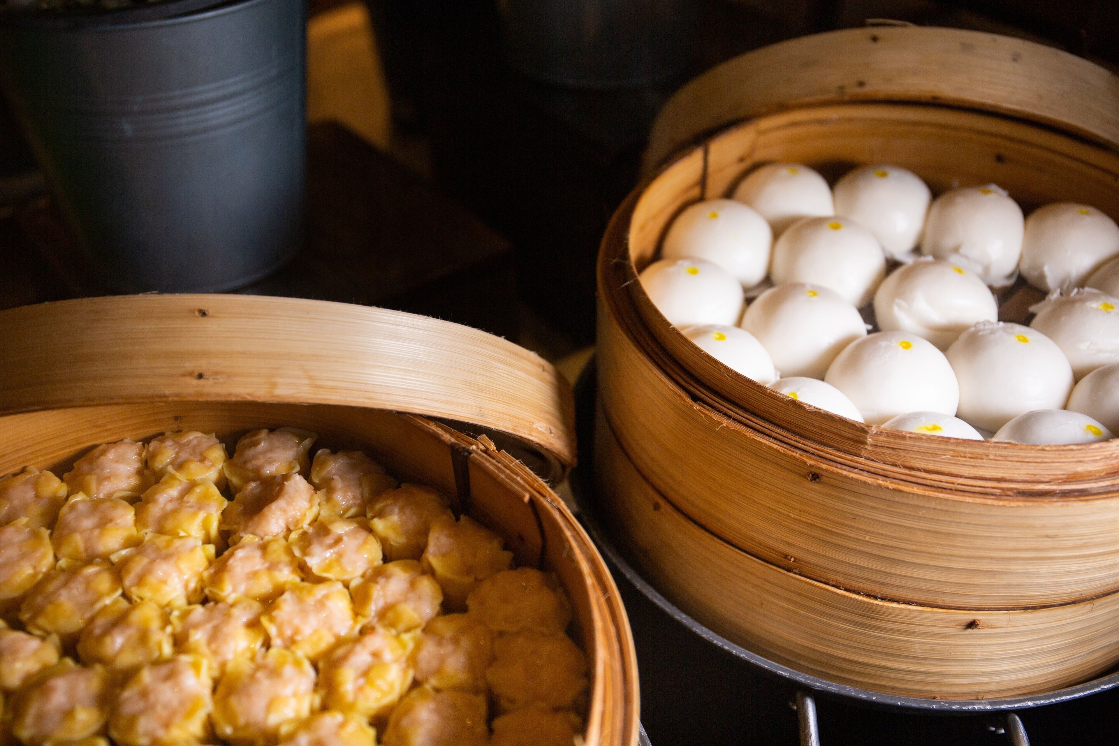 Two bamboo steamers filled with food items, likely dumplings or buns, placed on a rack.