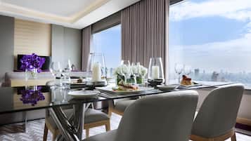 A modern dining area with a glass table, grey upholstered chairs, and a city view.