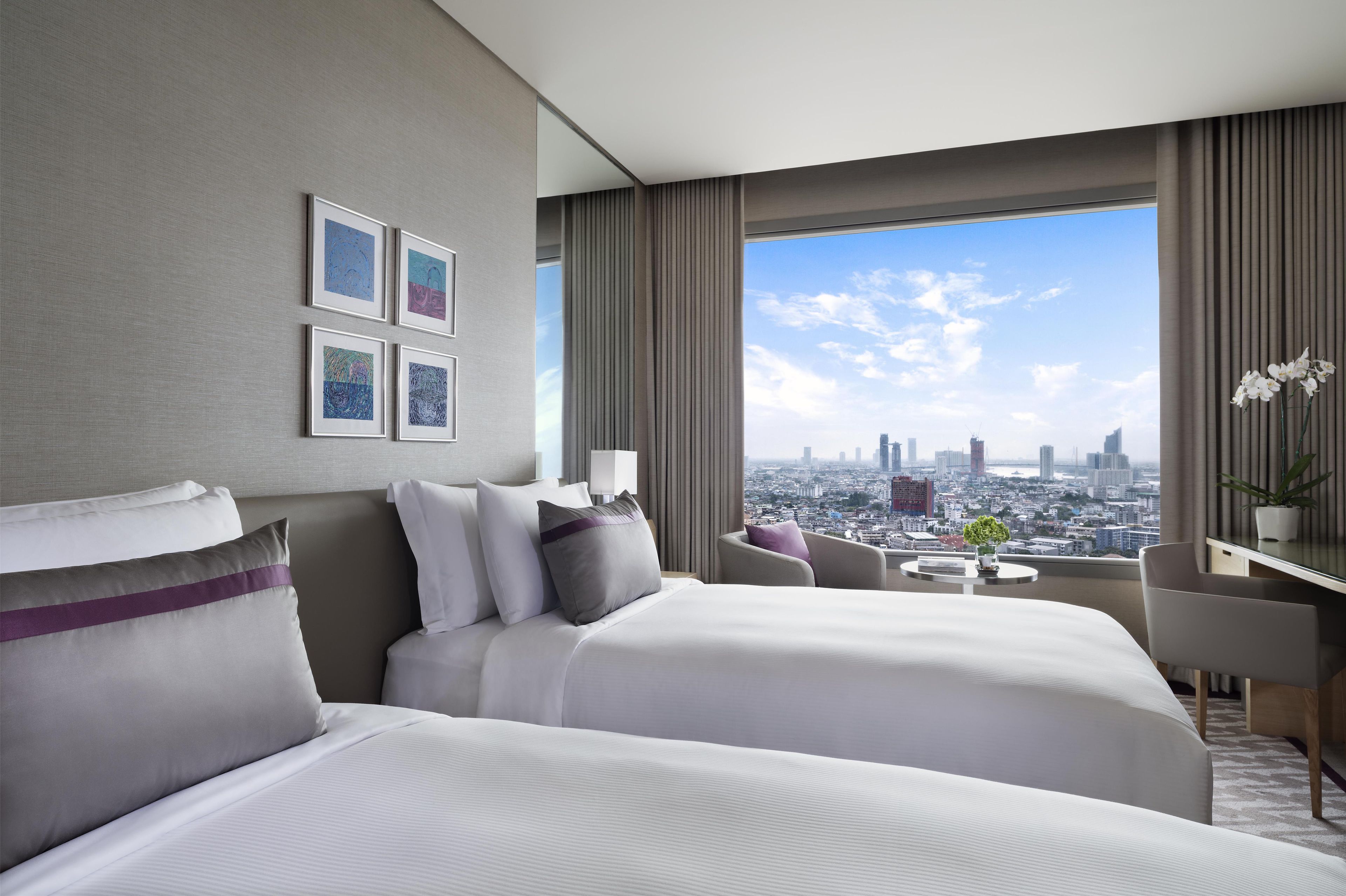 A hotel room with a city view, a bed, a desk, and a chair.