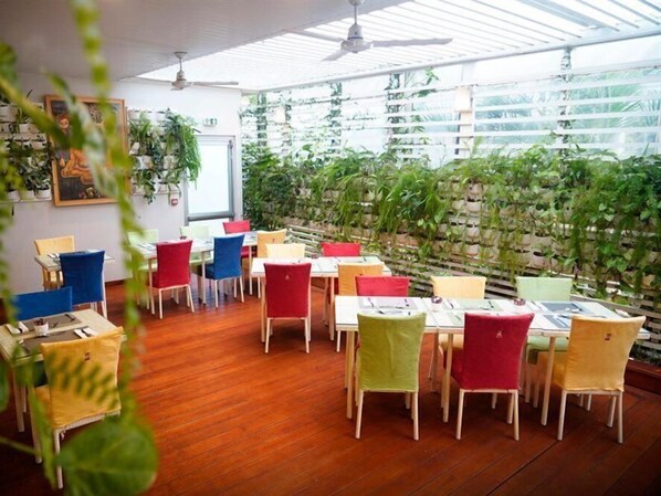 A restaurant with wooden flooring, colorful chairs, and a wall of hanging plants. - LE Lagon 2 (Dakar)