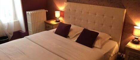 A hotel room with a large bed, two bedside lamps, and a patterned wall.