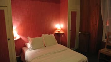 A room with a bed, two bedside lamps, a radiator, and a chair.