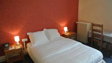 A neatly made bed with white linens, two bedside lamps, a wooden nightstand, a chair, and a radiator.