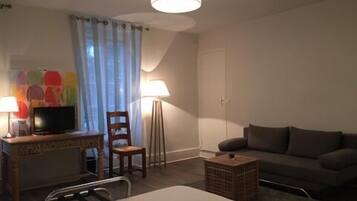 Een hotelkamer met een bed, een bureau met een televisie, een stoel, een vloerlamp en een bank.