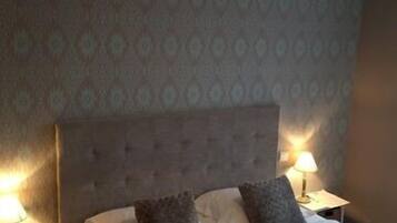 A bedroom with a large bed, two bedside tables, and a hanging lamp.