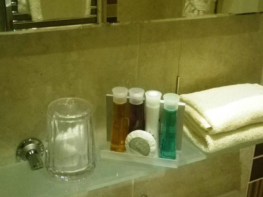 Een badkamer met een spiegel, handdoekhouder, wastafel en toiletartikelen.