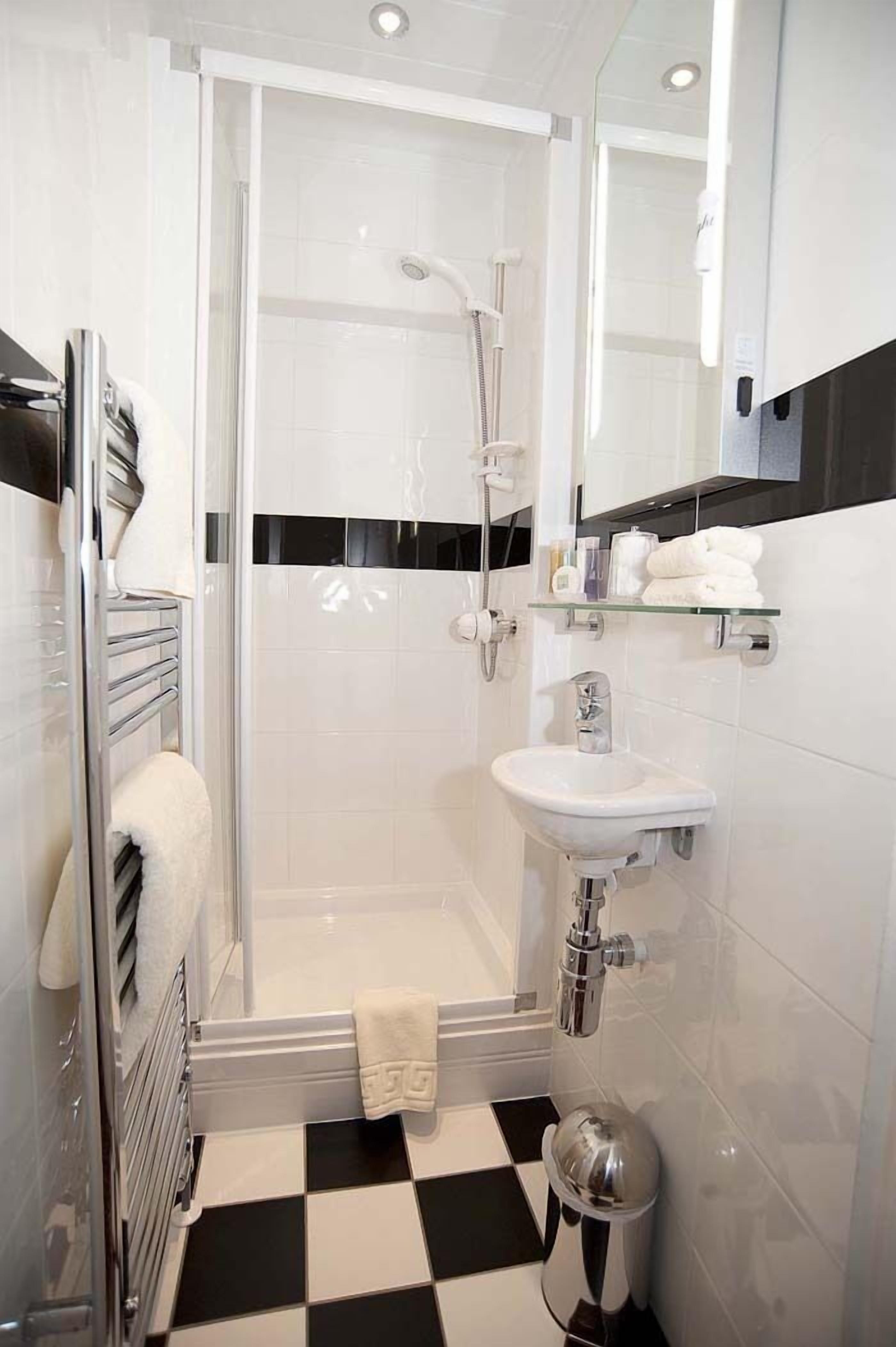Ein modernes Badezimmer mit einer Glaskabinentasse, einem weißen Waschbecken und einem Schachbrettfußboden.