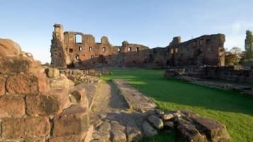 Una antigua estructura de piedra con ruinas y un patio cubierto de césped.