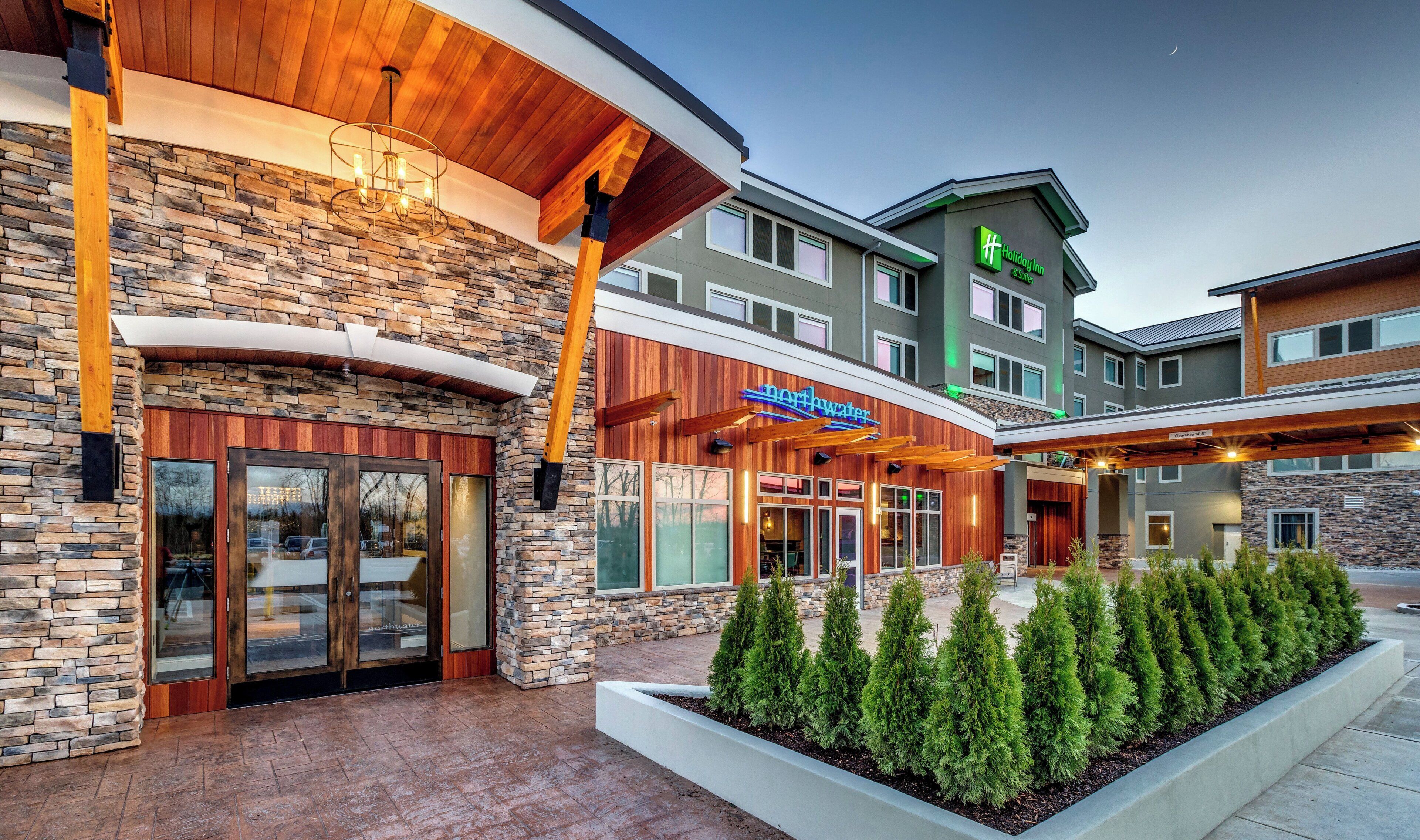 A Holiday Inn Express with a stone facade, a covered outdoor area, and a landscaped garden.