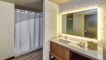 Un bany amb cortina de dutxa, un lavabo amb mirall i paper pintat.