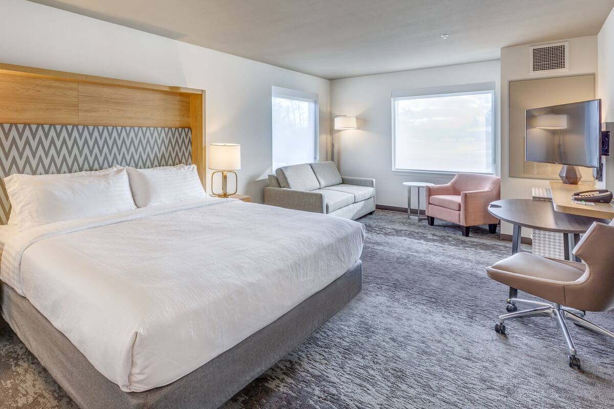 Una habitación de hotel con una cama grande, un escritorio, una silla y un televisor.