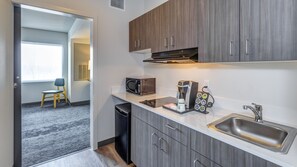 A compact kitchenette with a microwave, coffee maker, and a sink.