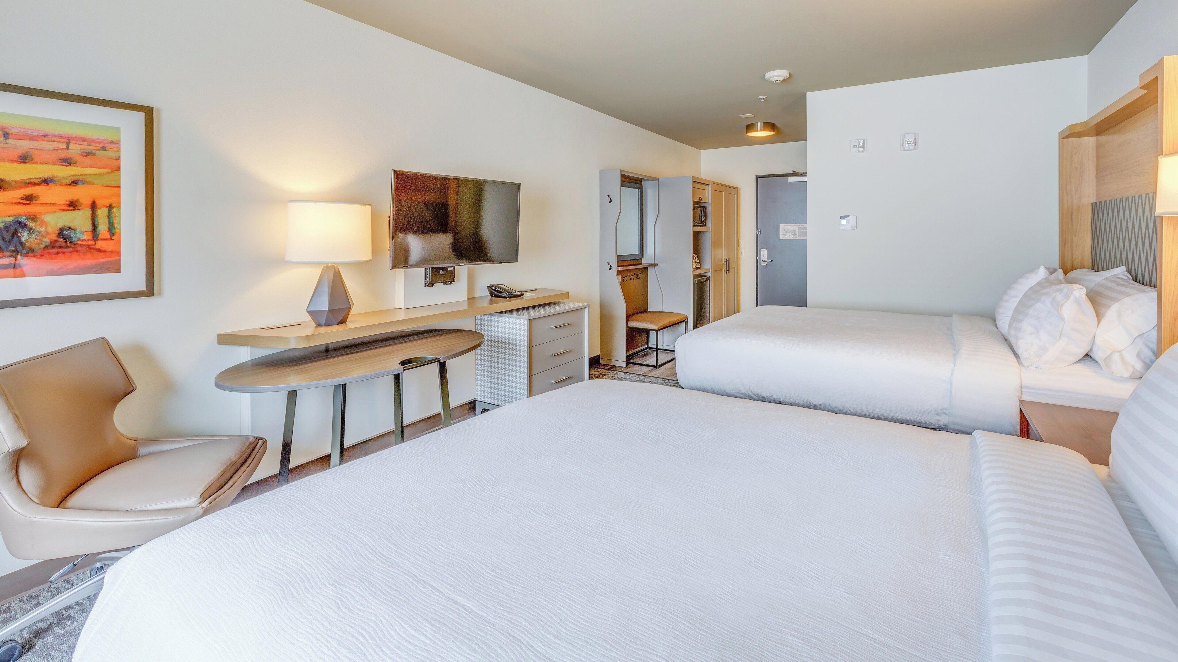 Ein Hotelzimmer mit Bett, Schreibtisch, Stuhl und Fernseher.