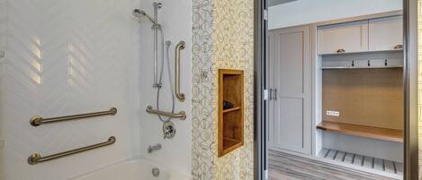 Un baño moderno con bañera, ducha y barras de apoyo.