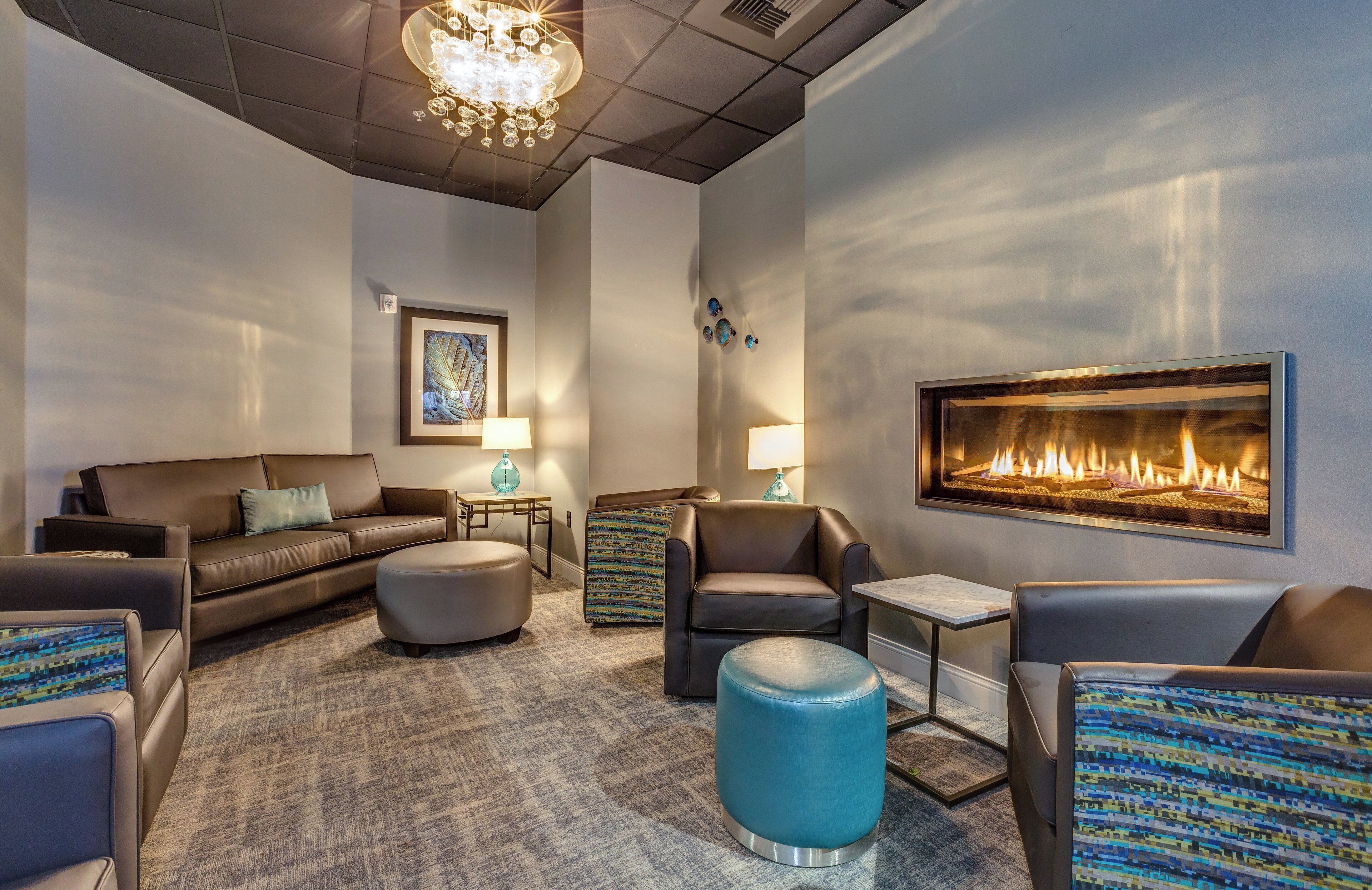 Ein stilvoller Lounge-Bereich mit Ledersofas, einem runden Hocker und einem Wandkamin.