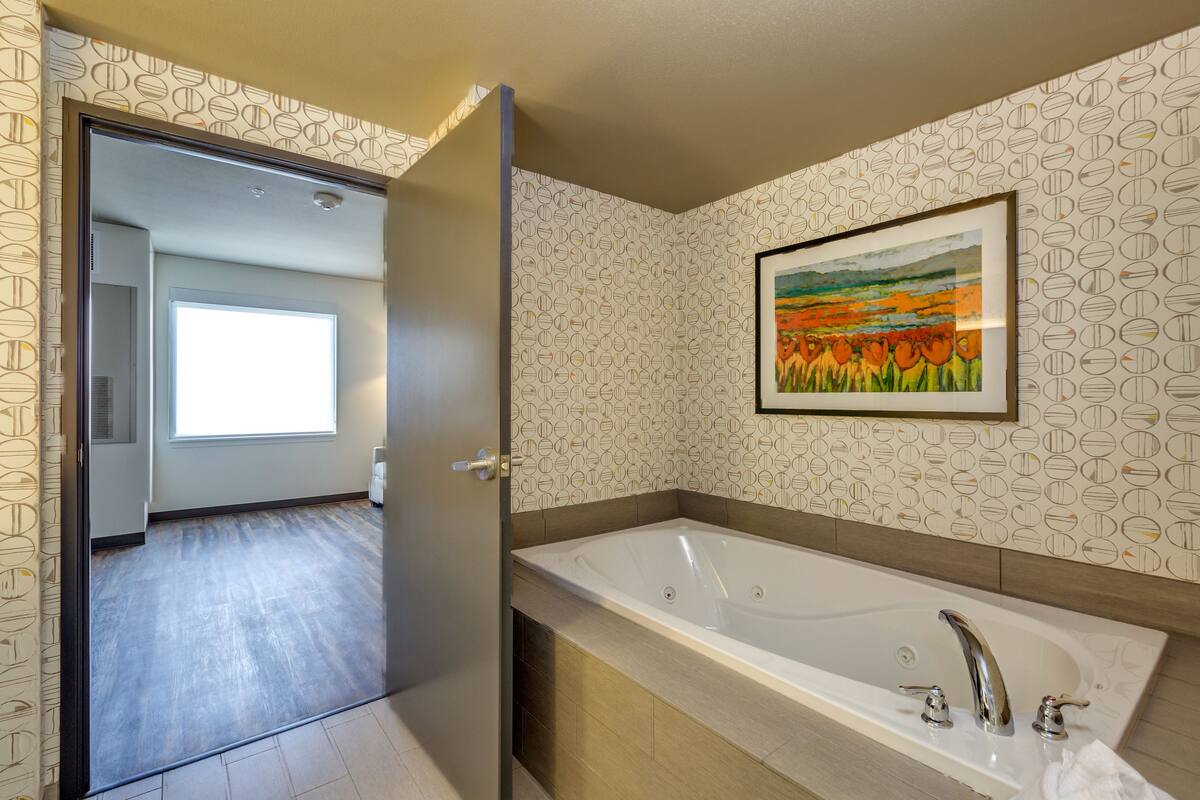 Un baño moderno con una bañera grande, zona de ducha y ventana que proporciona luz natural.