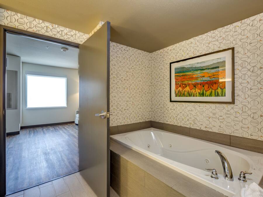 A modern bathroom with a large bathtub, a shower area, and a window providing natural light.