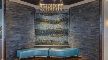 A modern interior with a stone wall, a bench, and a hanging light fixture.
