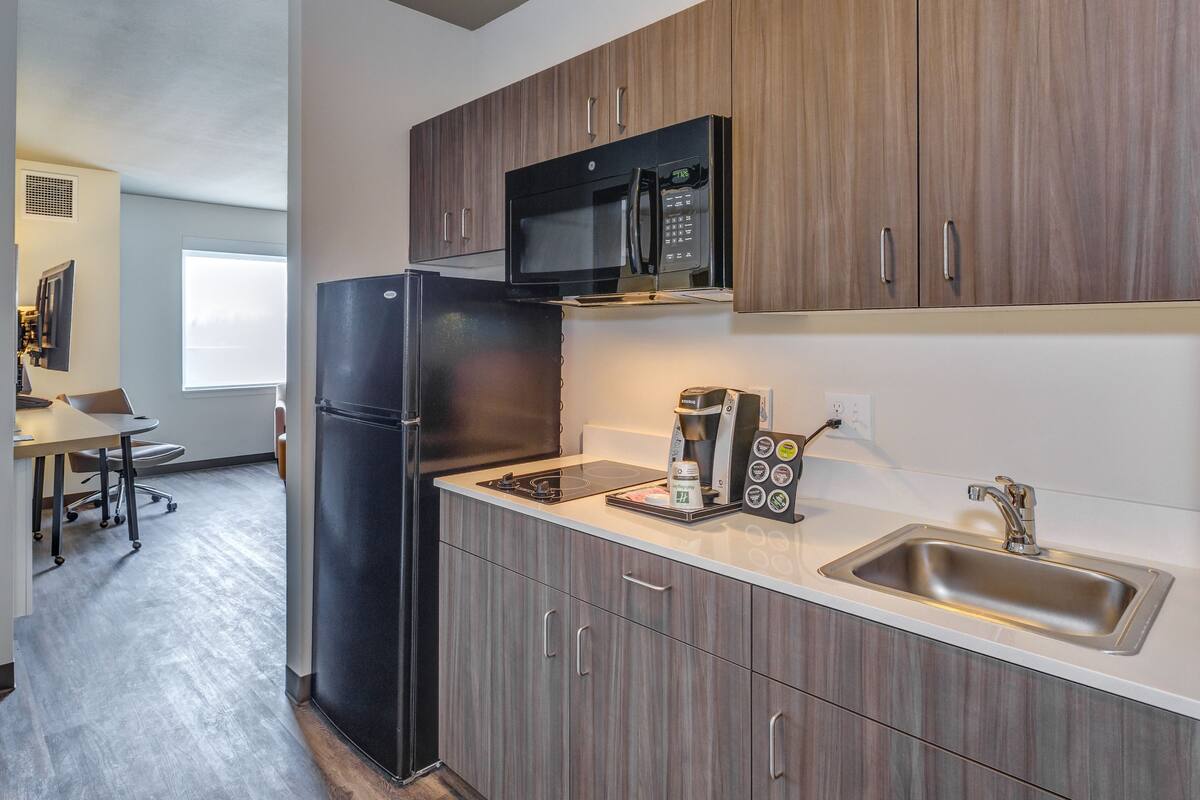 Una cocina moderna con refrigerador, microondas, cafetera y pileta.