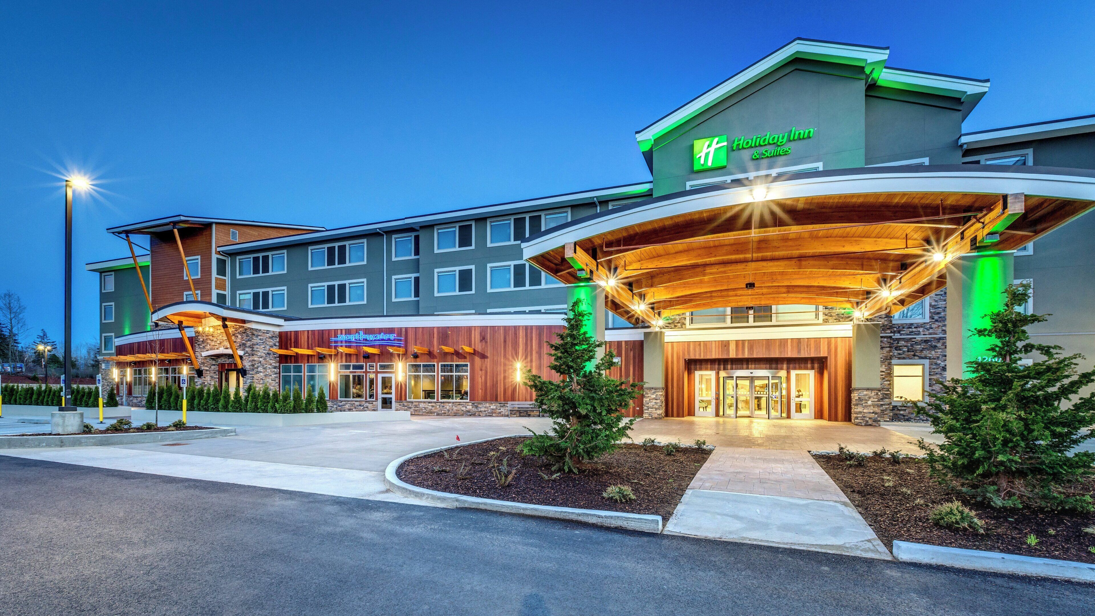 A Holiday Inn & Suites with a modern design, featuring a covered entrance and multiple levels.