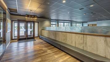 A reception area with a wooden bench, a glass partition, and a ceiling with recessed lighting.