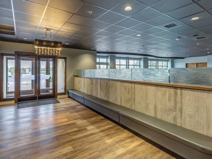 A reception area with a wooden bench, a glass partition, and a ceiling with recessed lighting.