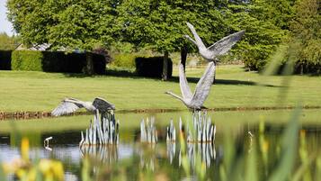 A pond with statues of birds and a tree in the background.