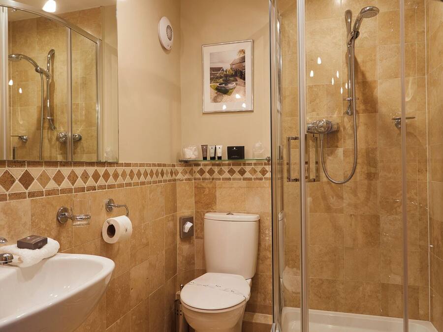 A bathroom with a shower, toilet, sink, and a mirror.