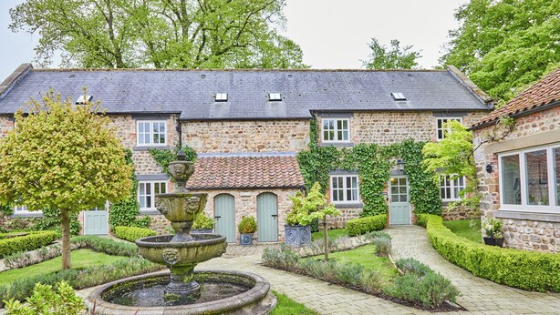 A stone building with a garden, including a fountain and well-kept hedges. - The Old Coach House (Ripon)