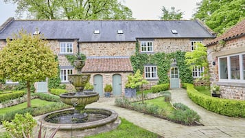 Traditional architecture meets serene gardens, featuring a central fountain and beautifully manicured hedges.