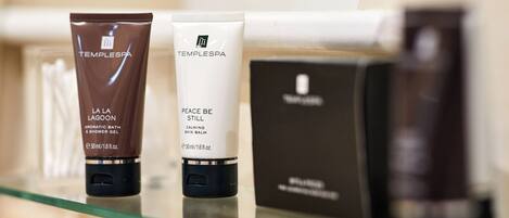 Three skincare products on a glass shelf.