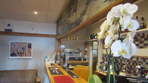 Un coin bar accueillant avec un comptoir en bois, un canapé et un tableau accroché au mur.