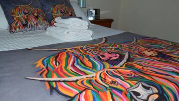 A bed with a colorful blanket, pillows with animal designs, and neatly folded white towels.