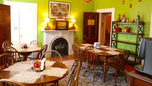 Un comedor con chimenea, una araña y una pared verde.