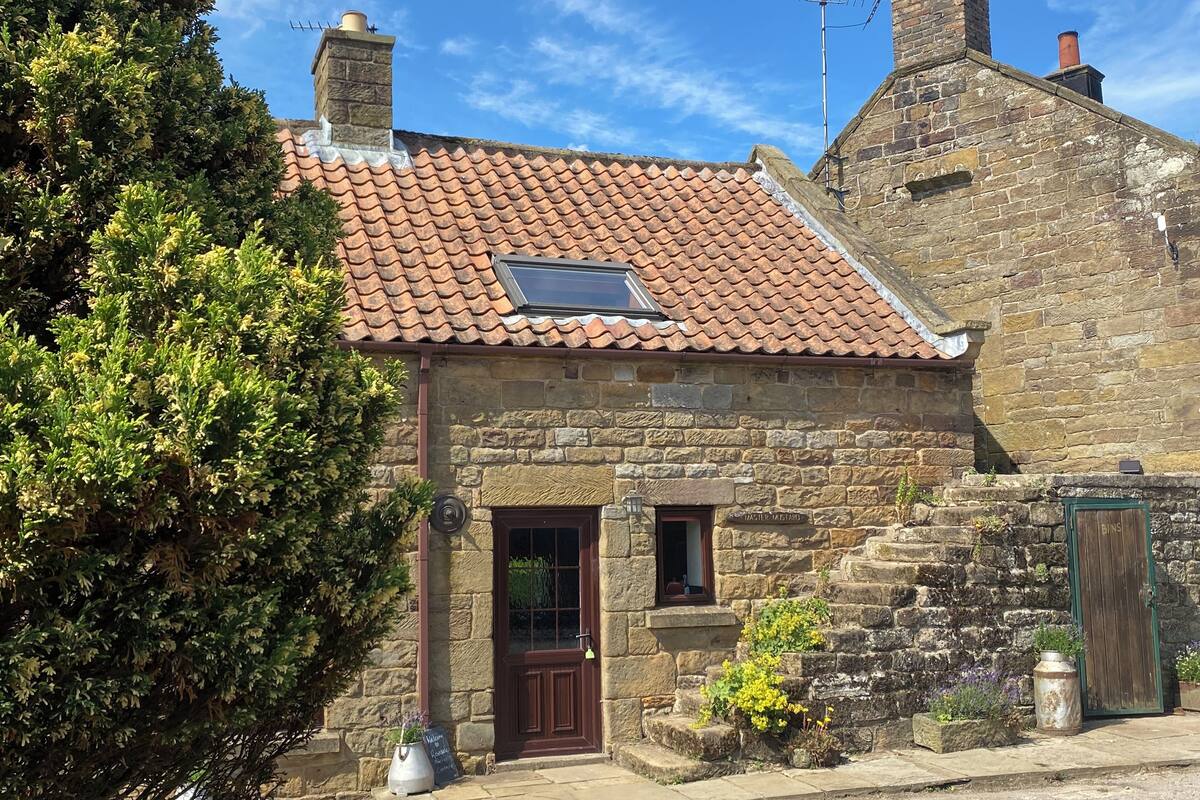 A stone building with a tiled roof, a wooden door, and a small window.