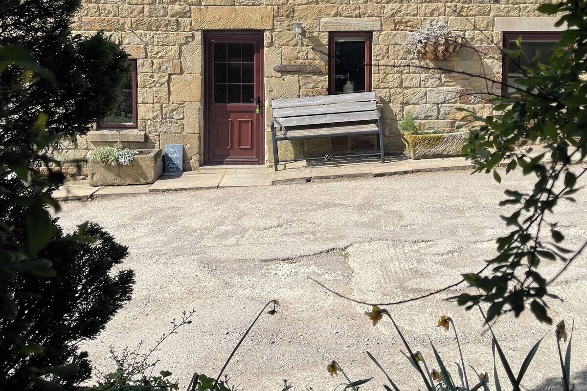 A stone building with a tiled roof, a wooden bench, and a sign that reads "Welcome to Court."