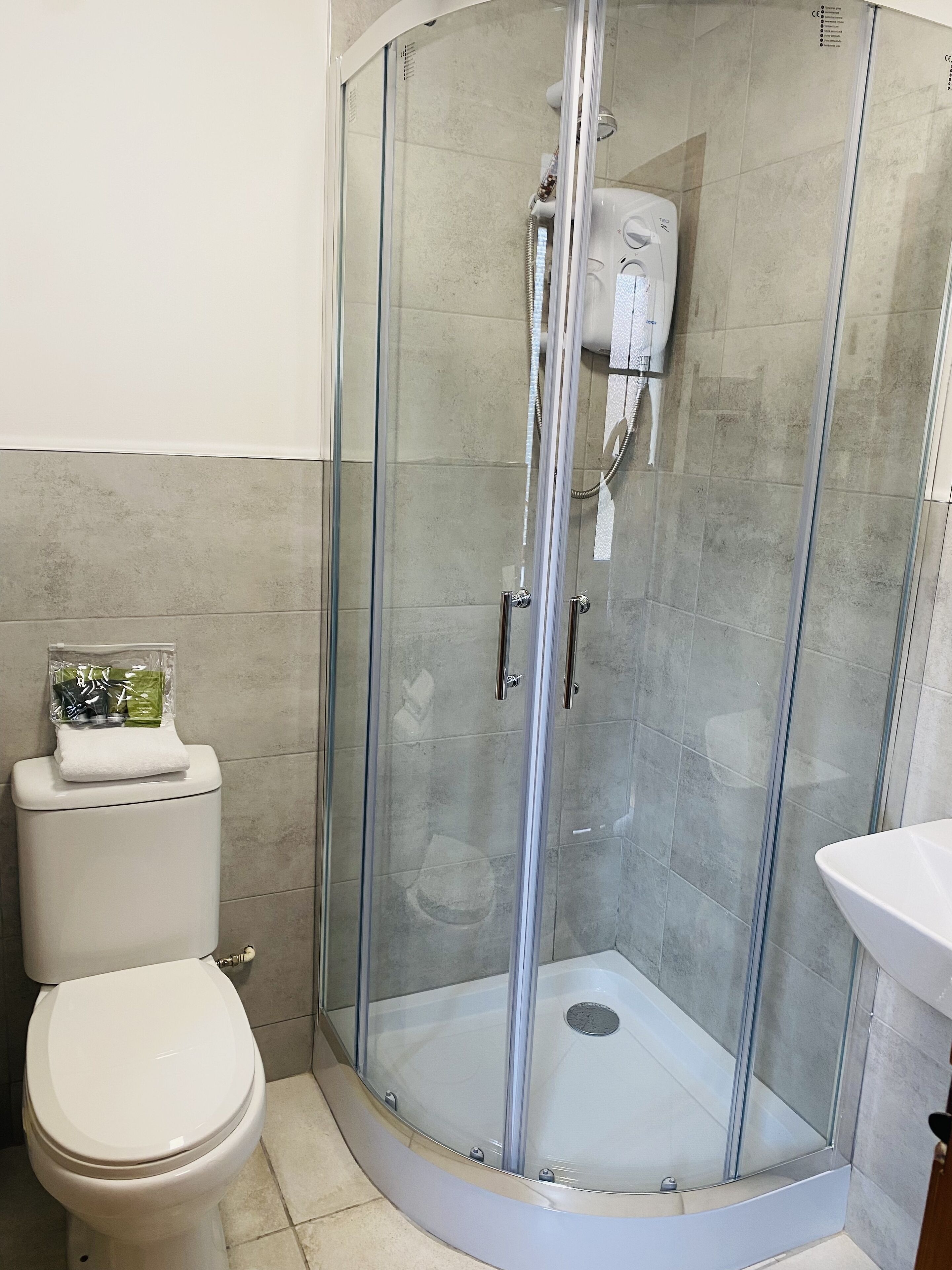 Een moderne badkamer met een glazen douchecabine, toilet en wastafel.