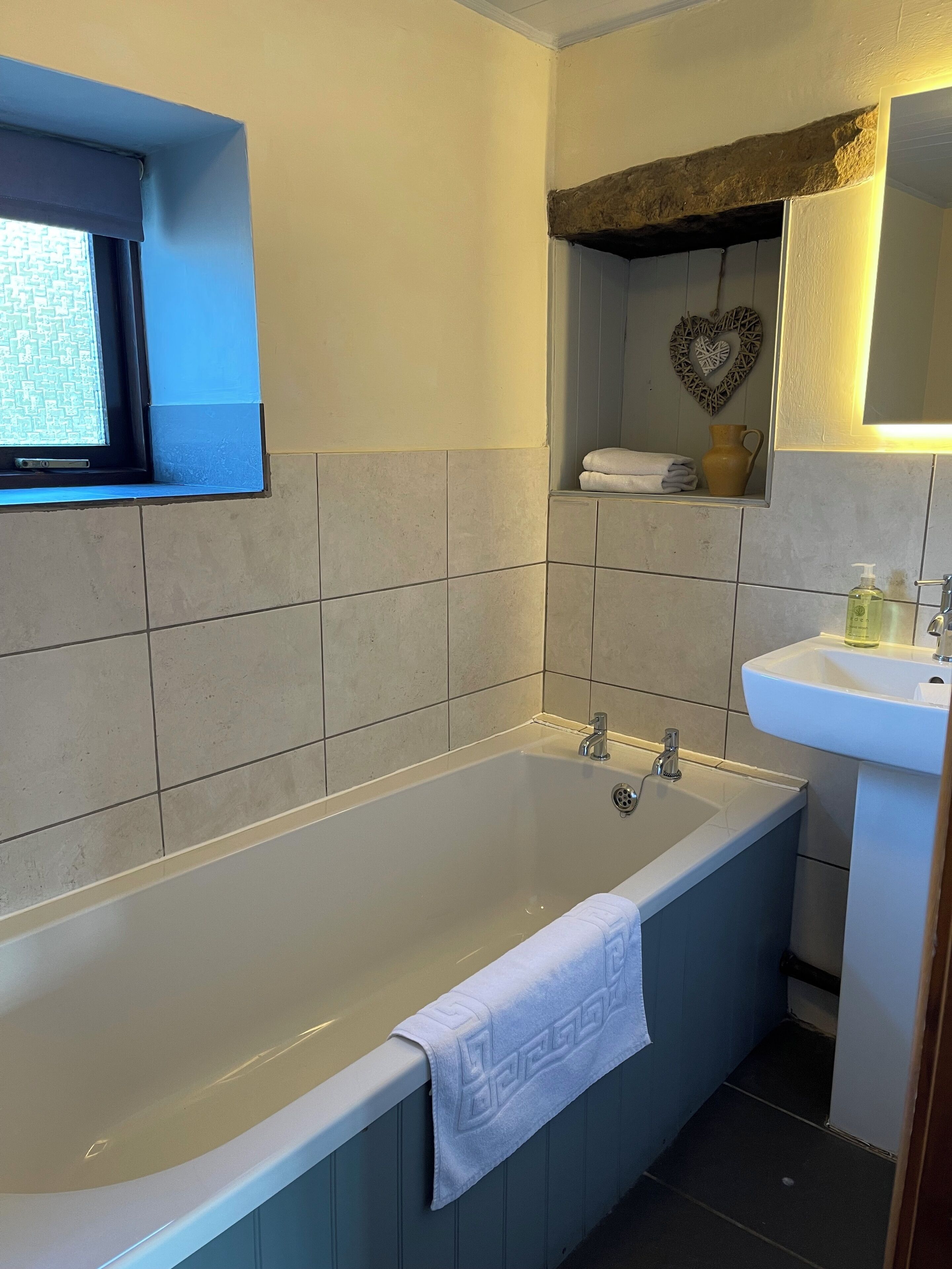 A bathroom with a bathtub, a sink, and a window.