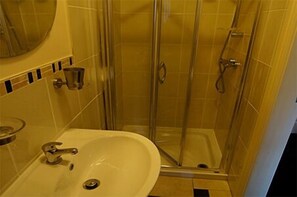 A bathroom with a glass-enclosed shower, a sink, and a mirror. - South Beach Apartments (Blackpool)