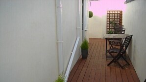 A narrow wooden deck with a table and chairs, surrounded by walls and a small potted plant. - South Beach Apartments (Blackpool)