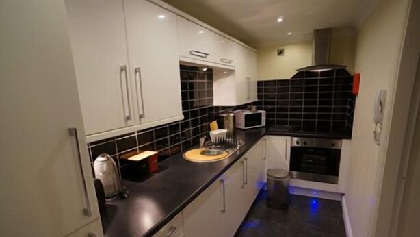 A compact kitchen with white cabinets, a black countertop, and a microwave. - South Beach Apartments (Blackpool)