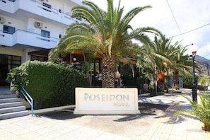 A hotel entrance with a sign reading 'POSEIDON HOTEL,' palm trees, and a staircase leading to the building. - Poseidon Hotel (Malevizi)