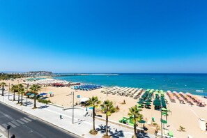 A beach with rows of umbrellas and sun loungers, a clear blue sky, and the sea. - Poseidon Hotel (Malevizi)