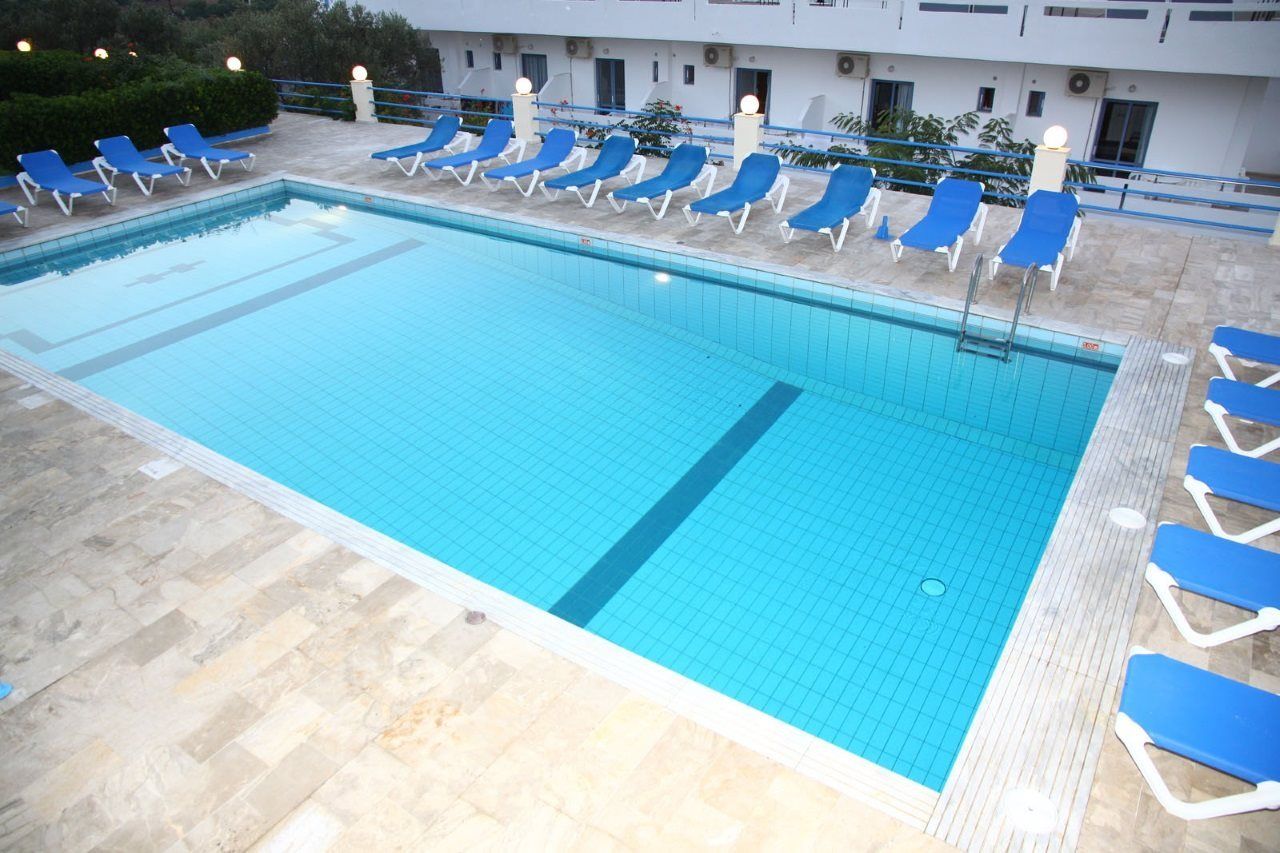En swimmingpool med blå liggestole og en fliseterrasse.
