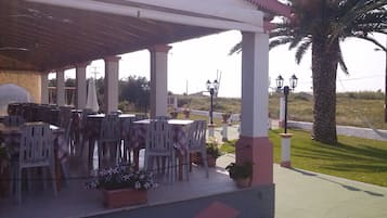 Un patio al aire libre con mesas y sillas, un área de estar cubierta y vistas del paisaje circundante.