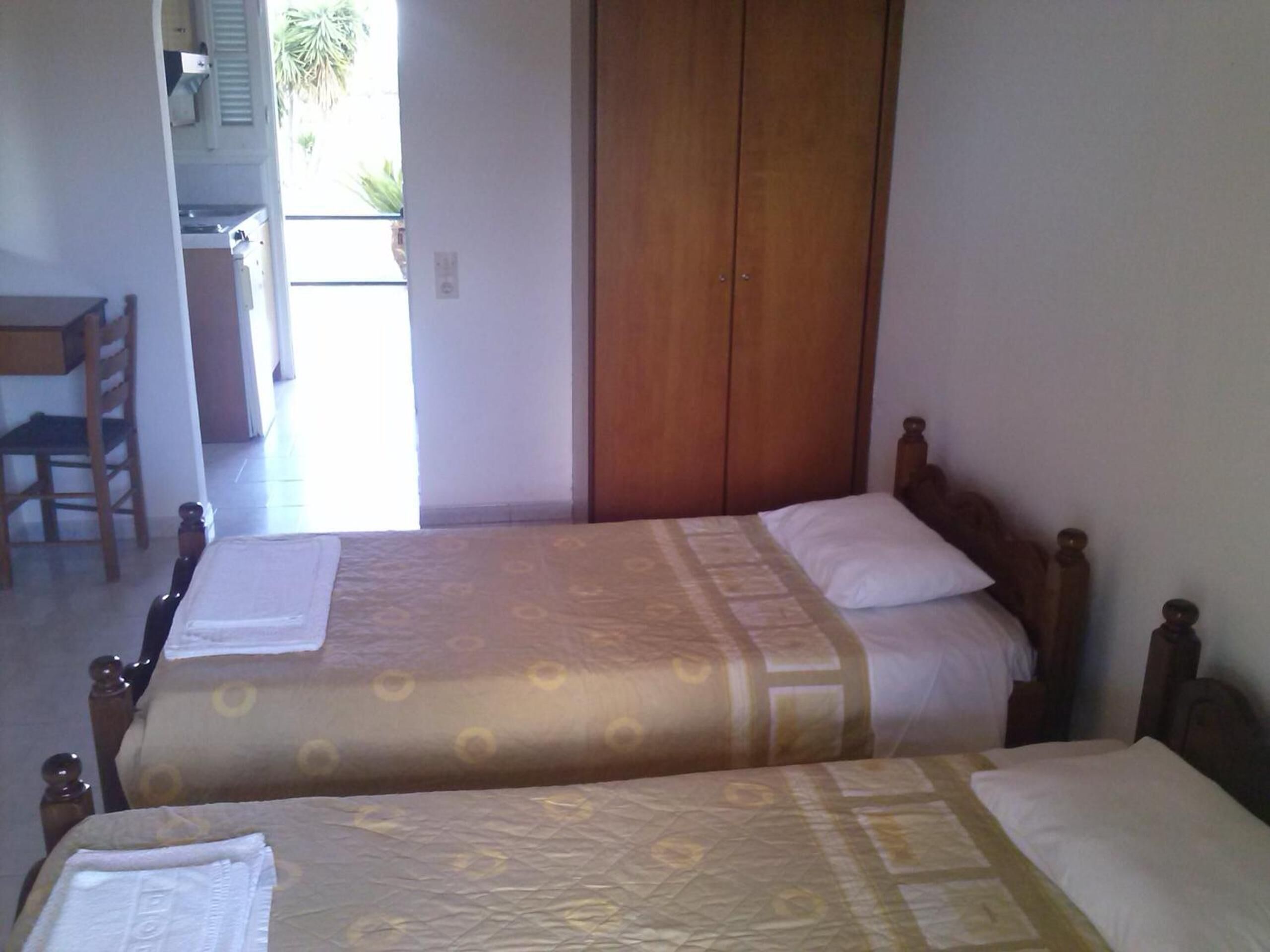 Une chambre avec deux lits, une armoire en bois et une chaise.