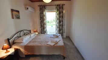 Un dormitorio con cama, dos lámparas de noche, aire acondicionado de pared y ventana con cortinas.