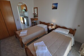A hotel room with two beds, a small desk, a mirror, and a picture on the wall. - Libertys Studios (Corfu)