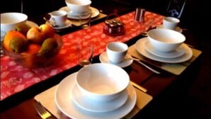 A table set with white bowls, plates, and cutlery. - LA B and B Guest Accommodation (Chichester)