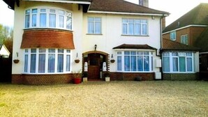 A two-story house with a brick facade, large windows, and a gravel driveway. - LA B and B Guest Accommodation (Chichester)